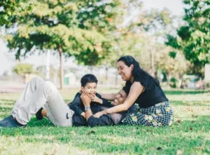 Keluarga bahagia bermain bersama di taman sebagai cara menjaga kesehatan mental