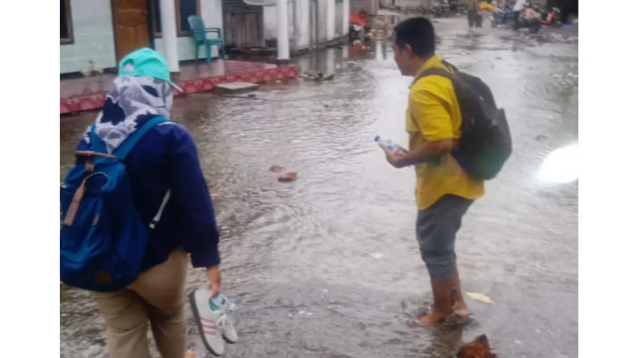 Asesor pendidikan terpaksa menggulung celana untuk melintasi banjir rob saat bertugas di Desa Jorjoga, Taliabu Utara.