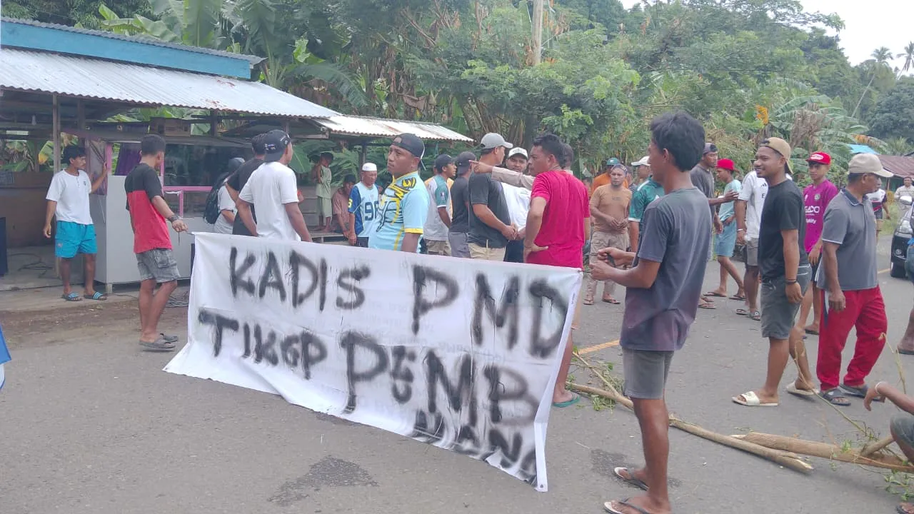 LUMPUL TOTAL: Massa aksi dari Desa Gita Raja melakukan pemblokiran jalan lintas utama di Tidore Kepulauan, Kamis (12/2/2026). Aksi ini merupakan bentuk protes keras warga yang menuntut pencopotan Kepala Desa Ade M. Rasid atas dugaan tindakan amoral dan desakan agar Walikota mencopot Kadis PMD yang dinilai melakukan pembohongan publik terkait janji pemecatan Kades. (Source : Agung Selang/Jurnalis Balengko)