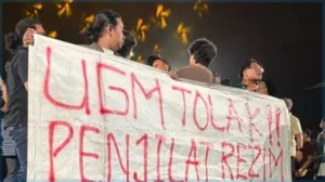 Massa aksi membentangkan spanduk berisi kritik tajam dan penolakan terhadap Budiman Sudjatmiko serta Nusron Wahid di tengah forum diskusi "Pancasila Pemersatu Bangsa" di GIK UGM, Yogyakarta, Senin (15/6/2026). Ketegangan ini memaksa panitia dan aparat keamanan mengevakuasi para pejabat negara tersebut dari lokasi acara. (Foto: Istimewa)